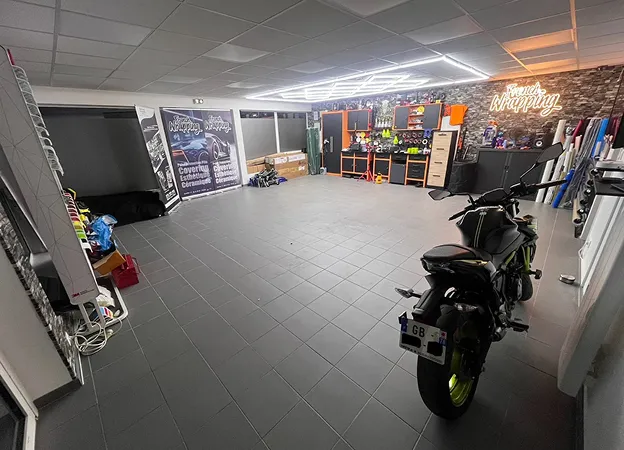 Intérieur d'atelier de covering automobile avec moto, outils, et enseigne néon French Wrapping à Maisons-Laffitte dans les Yvelines 78