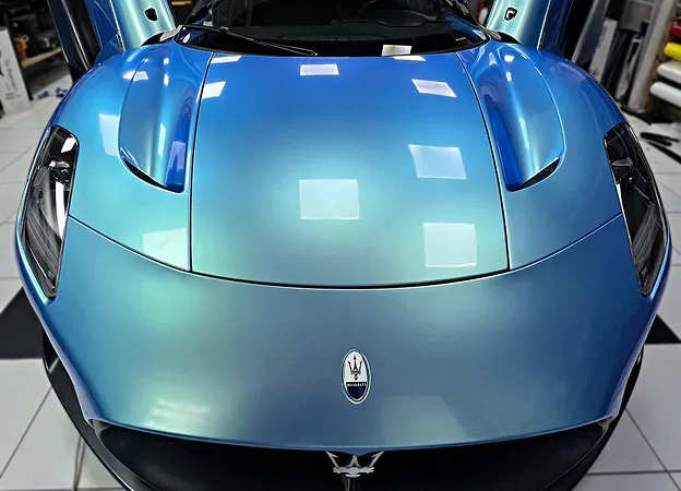 Maserati MC20 bleu-vert iridescent avec les portes en élytre ouvertes, vue de face à Maisons-Laffitte dans les Yvelines 78