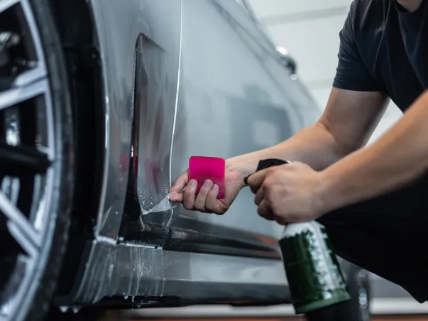 Homme appliquant un film de protection transparent sur la carrosserie d'une voiture à Maisons-Laffitte dans les Yvelines 78