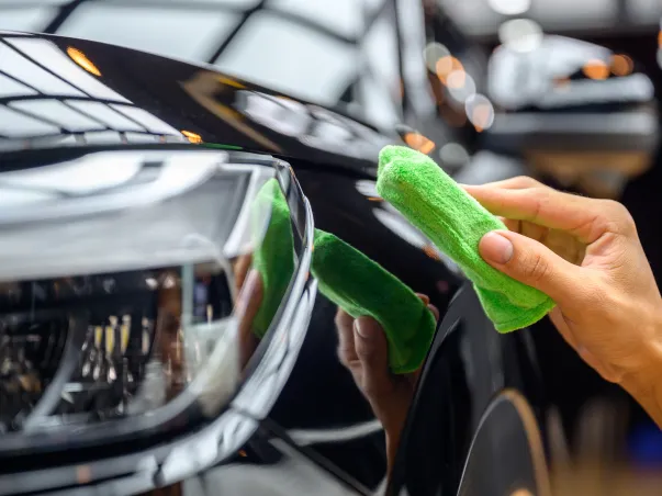 Main nettoyant une voiture noire brillante avec un chiffon vert à Maisons-Laffitte dans les Yvelines 78