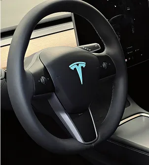 Volant Tesla noir avec un logo Tesla bleu vif et un écran à Maisons-Laffitte dans les Yvelines 78