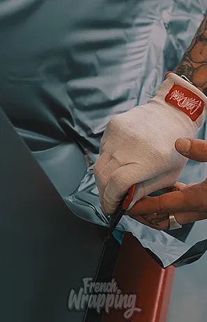Main gantée coupant avec un cutter le film adhésif d'un véhicule à Maisons-Laffitte dans les Yvelines 78