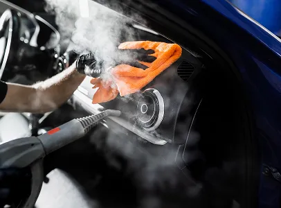 Nettoyage à la vapeur de l'intérieur d'une voiture avec une serviette orange à Maisons-Laffitte dans les Yvelines 78
