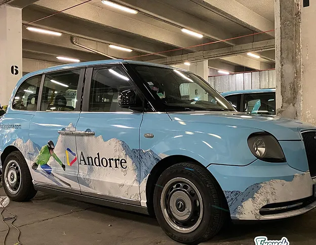 Taxi bleu clair Andorra avec skieur et montagnes, dans un parking à Maisons-Laffite dans les Yvelines 78