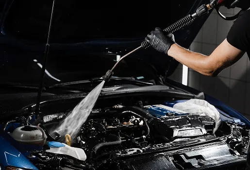 Mécanicien lavant le moteur d'une voiture bleue avec un nettoyeur haute pression à Maisons-Laffitte dans les Yvelines 78