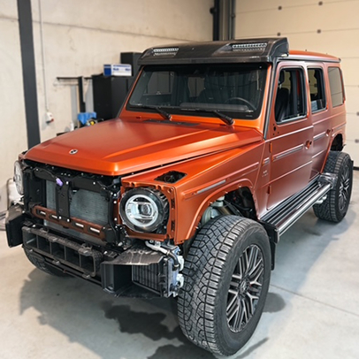 Homme appliquant un film de protection sur le côté d'une Porsche noire.